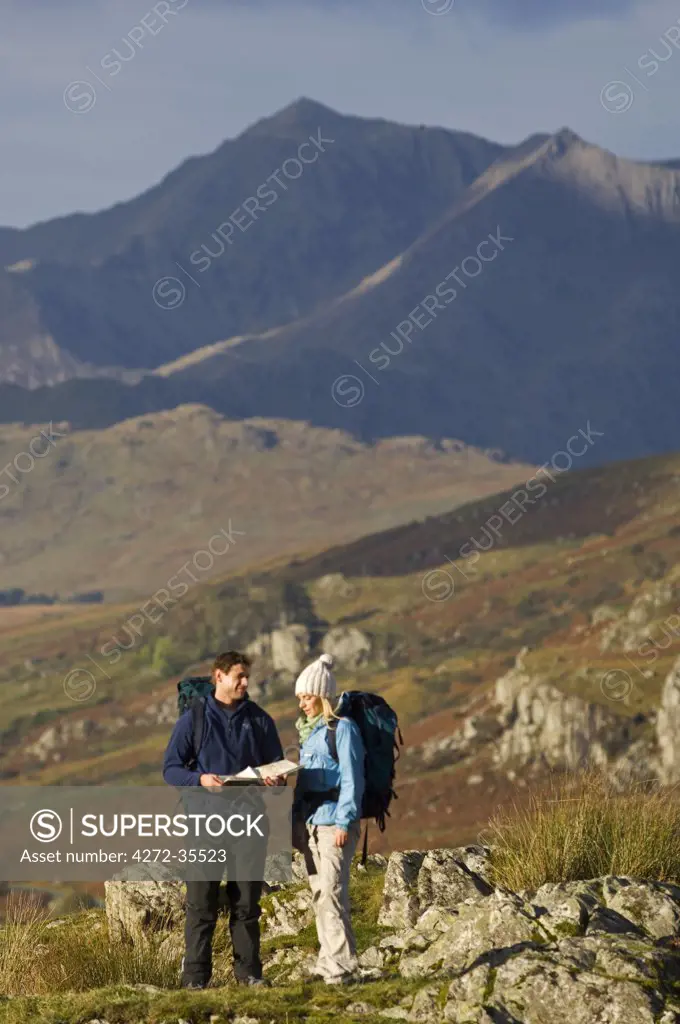 North Wales, Snowdonia.  A man and woman stop to look at their map whilst hiking in Snowdonia.  (MR)