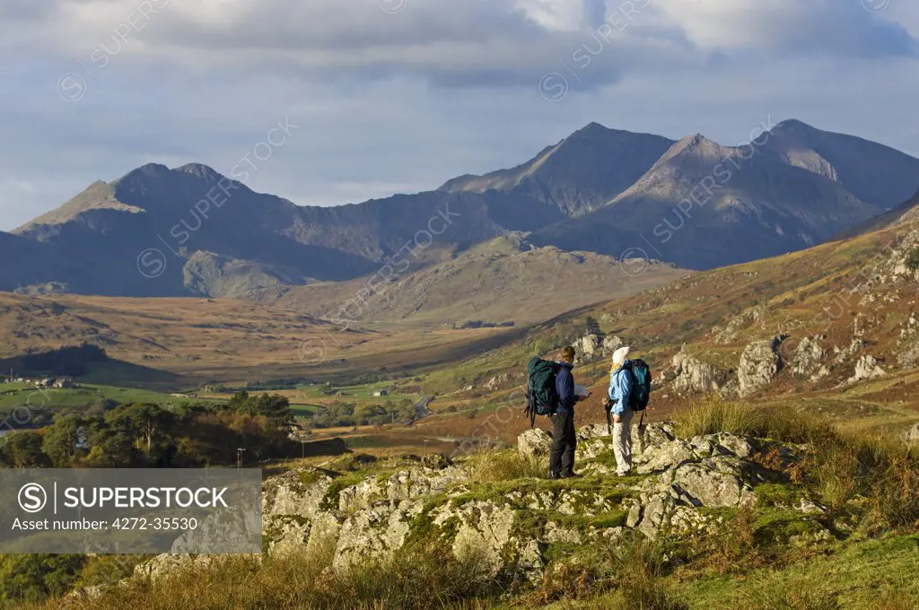 North Wales, Snowdonia.  A man and woman stop to look at their map whilst hiking in Snowdonia.  (MR)