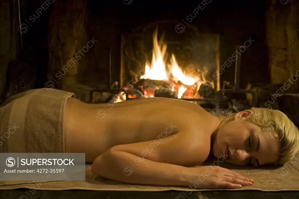 Gilar Farm, Snowdonia, North Wales. A girl relaxes after a massage in front of the open fire.  (MR)