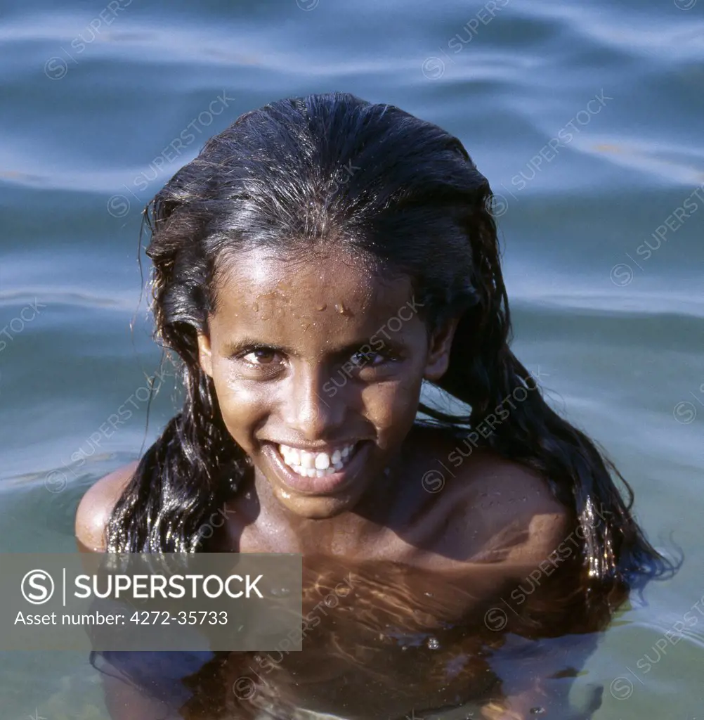 A pretty young Socotran girl enjoys swimming in a large rock pool at Ghoubah. This tidal pool is 124 feet deep and is fed underground from the sea almost half a mile away.
