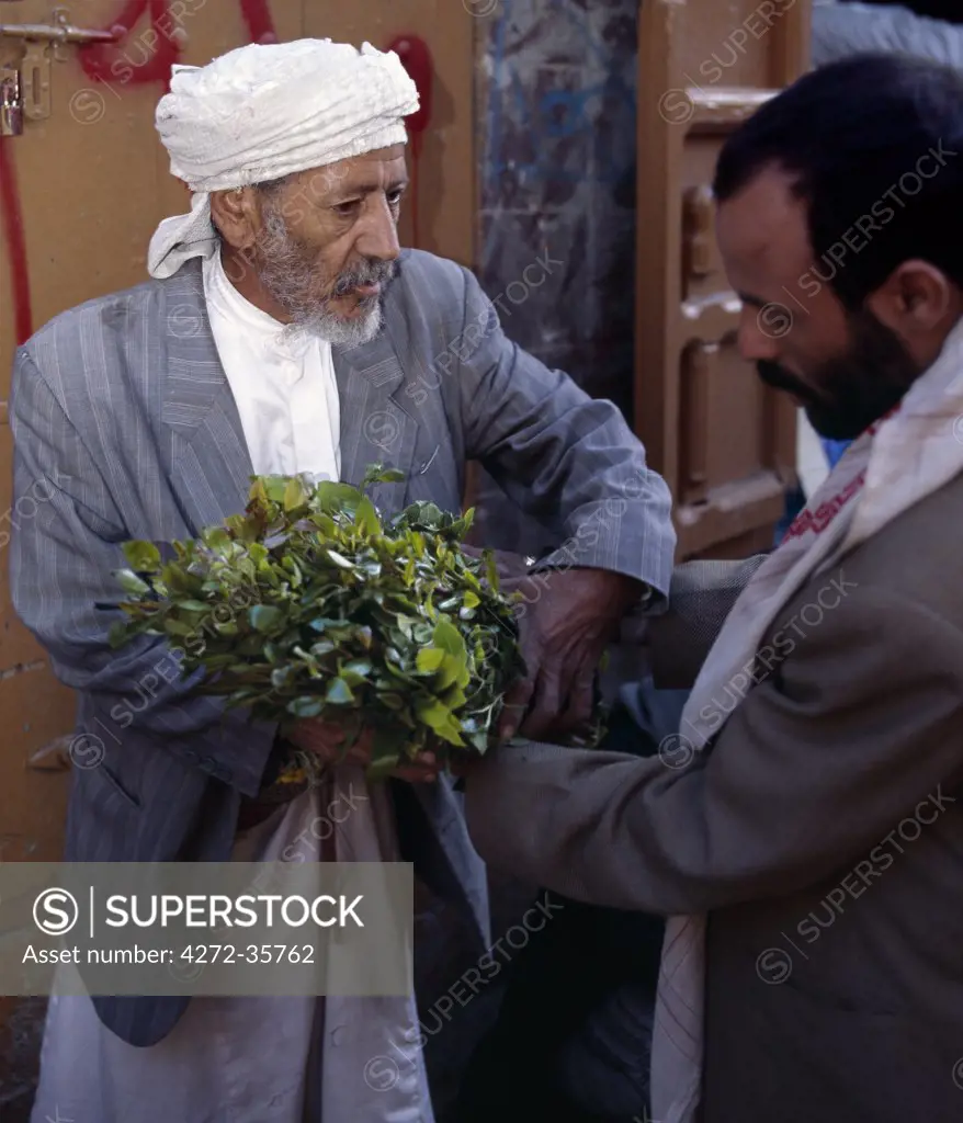 A Yemeni man buys qat in the Suq in old Sanaa. In the absence of liquor in this strictly Muslim state, most adult males chew the young leaves of the plant as a mild stimulant.  Originating from East Africa, the plant is grown in Yemen under irrigation.