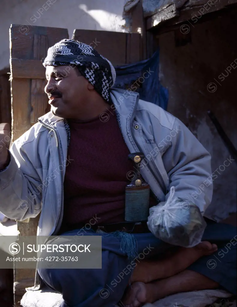 A stallholder offers qat for sale in a plastic bag in the Suq at old Sanaa. In the absence of liquor in this strictly Muslim state, most adult males chew the young leaves of the plant as a mild stimulant.  Originating from East Africa, the plant is grown in Yemen under irrigation.