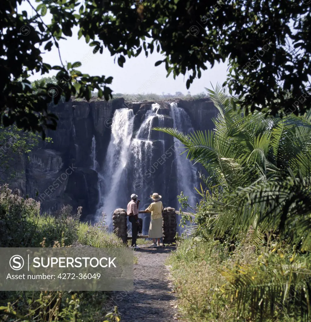 A visitor gazes at the magnificent Victoria Falls. ;The Falls are more than a mile wide and are one of the world's greatest natural wonders. The mighty Zambezi River drops over 300 feet in a thunderous roar with clouds of spray.