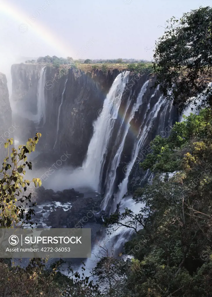 A rainbow arches over the magnificent Victoria Falls.  ;The Falls are more than a mile wide and are one of the world's greatest natural wonders. The mighty Zambezi River drops over 300 feet in a thunderous roar with clouds of spray.
