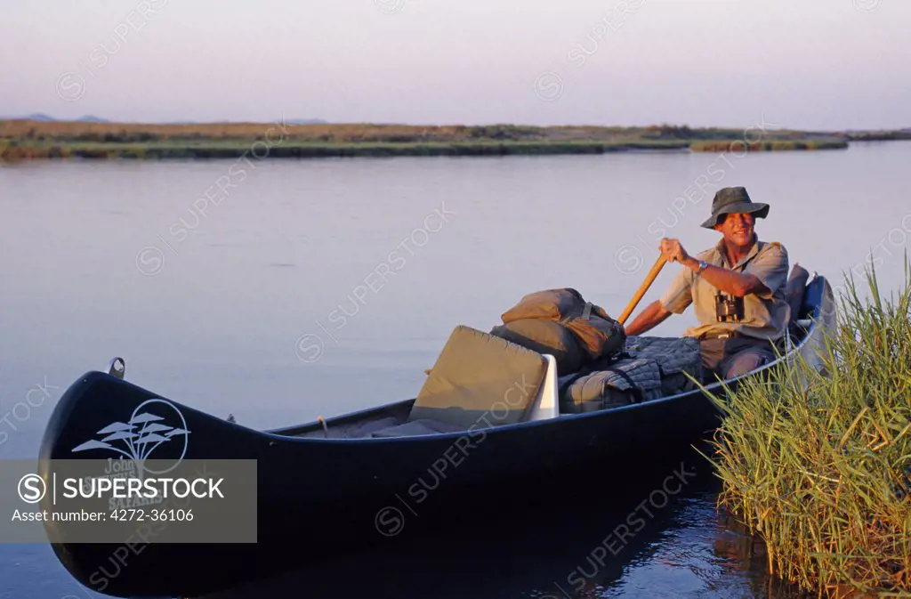 John Stevens paddling his canoe on the Zambezi at sunset. Mana Pools, Zimbabwe.