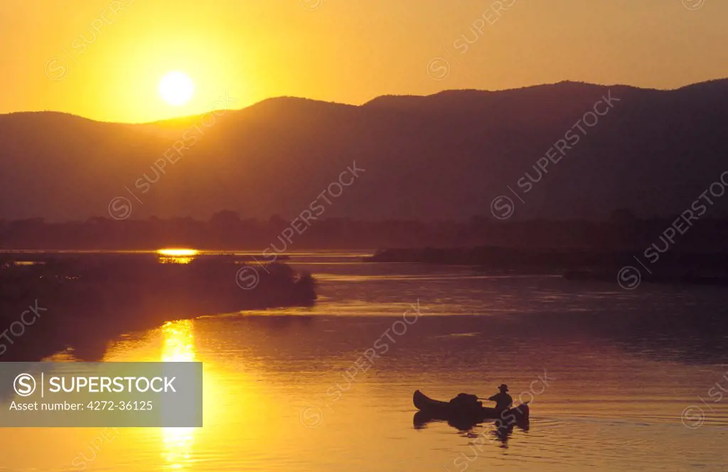 John Stevens paddling canoe on Zambezi from Mana pools, with Zambia in background.