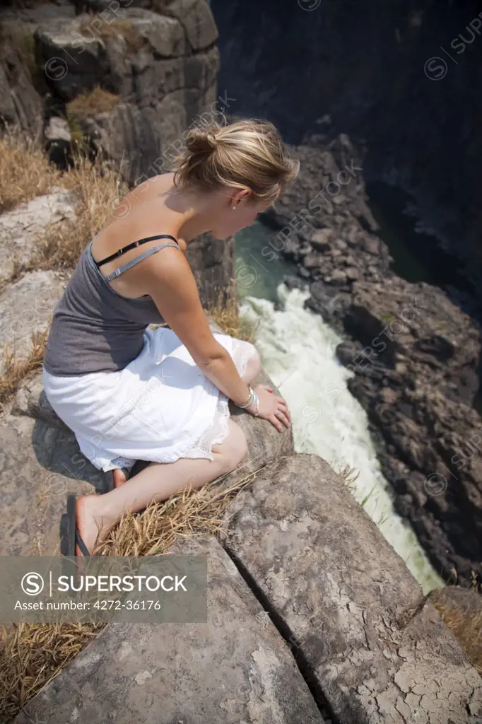 Zimbabwe, Victoria Falls. A young lady peers over the edge of Victoria Falls. MR