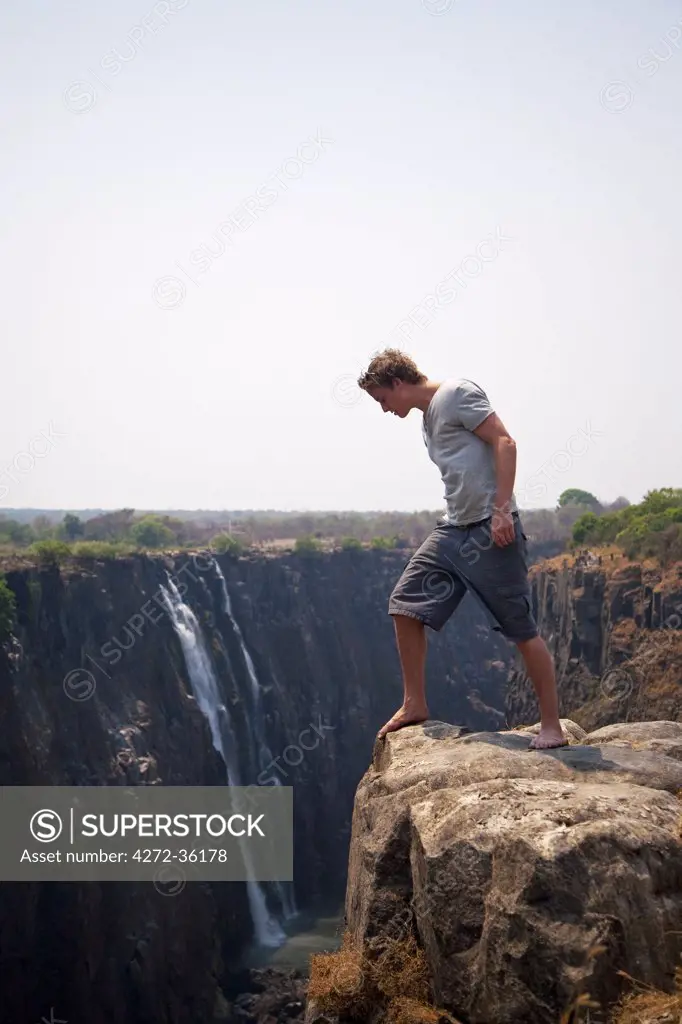 Zimbabwe, Victoria Falls. A man peers over the edge of Victoria Falls. MR.
