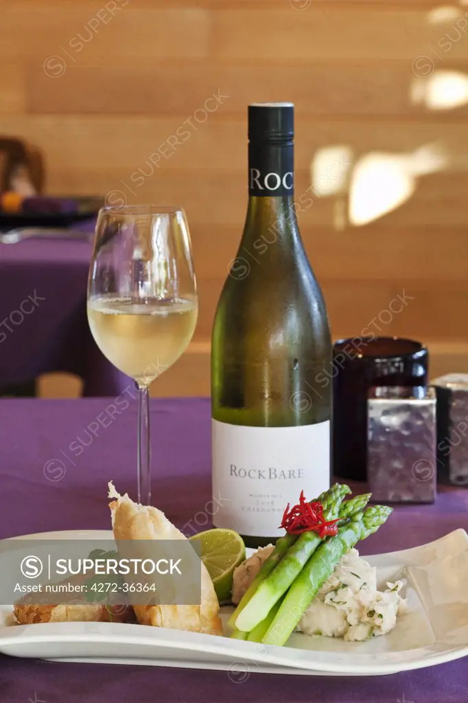 Australia, Queensland, Cairns.  Crispy Atlantc salmon with bottle of wine at Tamarind Restaurant.