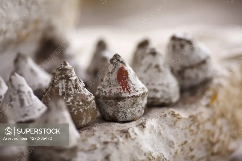 Small sculpture stupa images (tsha tsha) made of clay containing ashes of the dead, placed at the base of a prayer wheel at Drukgyel Dzong.