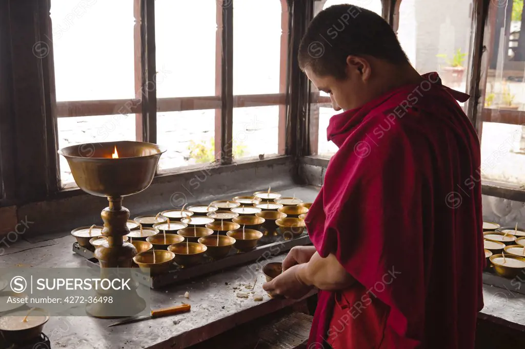 A young monk cleaning and filling the butter lamps at Tango Monastery.