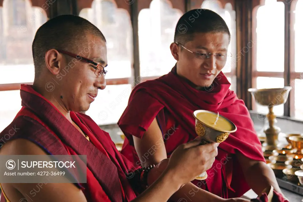Young monks cleaning and refilling butter lamps at Tango Monastery.