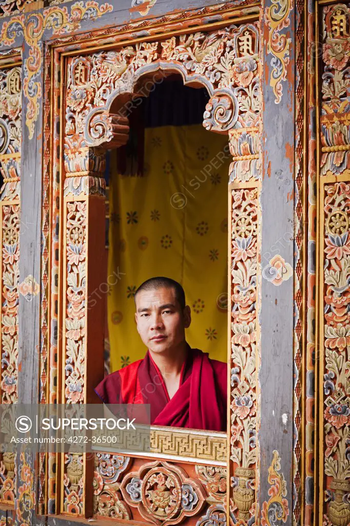 Young monk looking through one of the beautiful carved window frames at Tango Monastery.