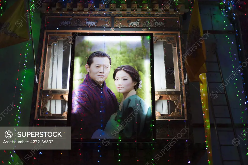 A large poster lit up on the side of a building in Thimphu showing the newly married King of Bhutan, and his Queen Consort, Jetsun Pema.