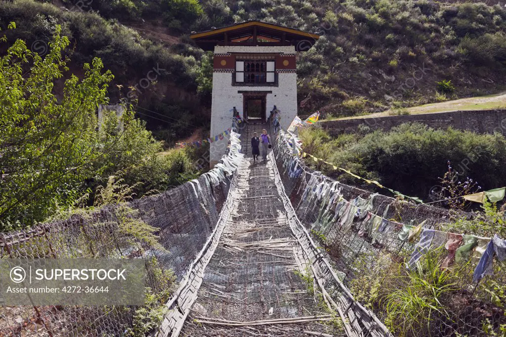 A tourist gingerly walking over the swaying iron suspension bridge at Tamchhog Lhakhang, a monastery built in the 14th century by Dewa Zangpo..
