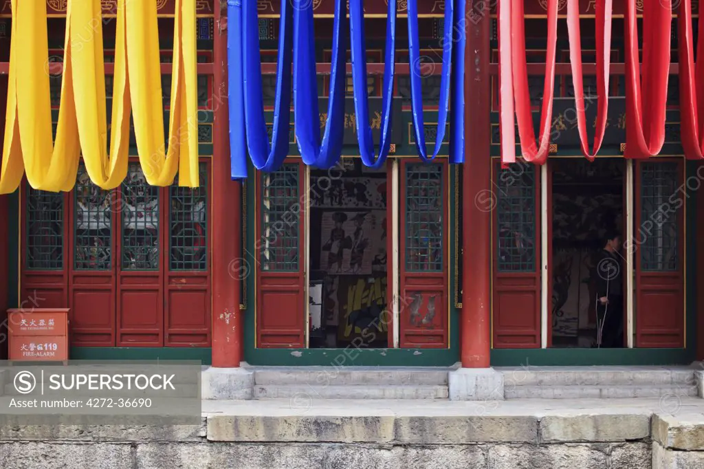 Red, yellow and blue drapes hang from a quayside building, located near the Long Bridge, North Palace Gate of the Summer Palace, Xibeiwang, Beijing, China.