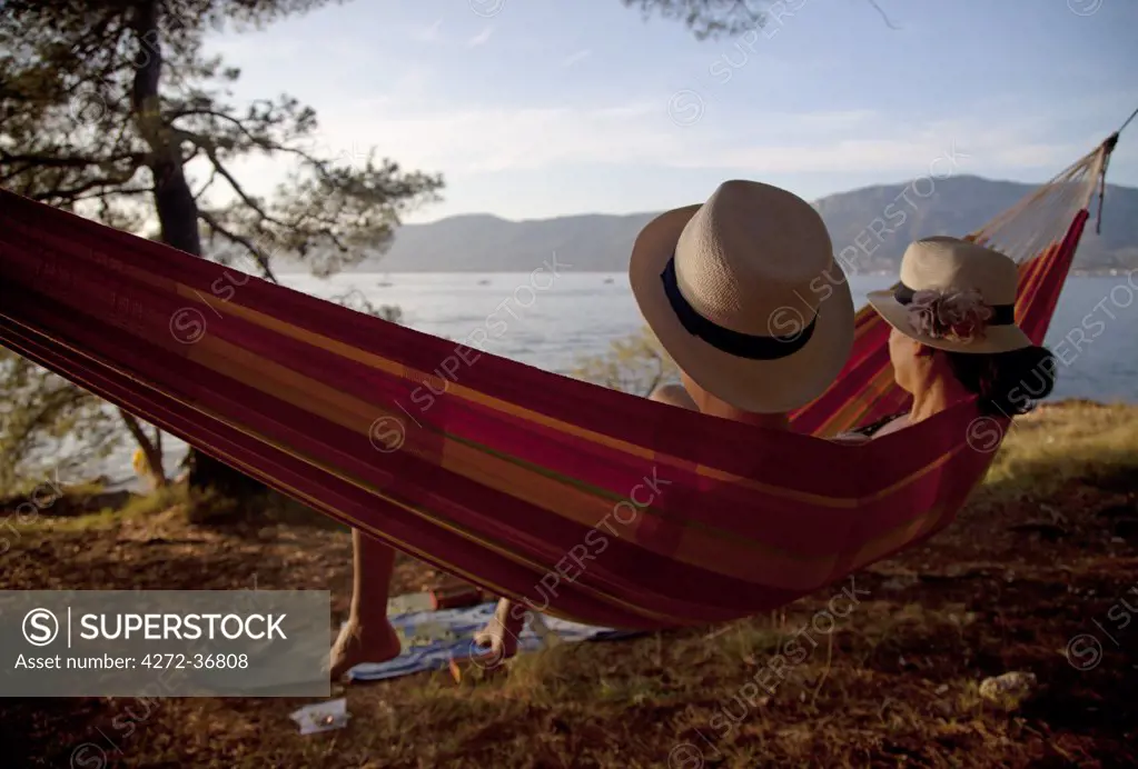 Croatia, Split, Central Europe. Two young women sunbathing on a hammock on one of the beaches in the suburbs. MR