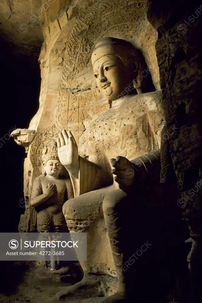 Visitor beside one of the Buddha statues at the 5th Century Yungang Caves, a series of Buddhist grottoes