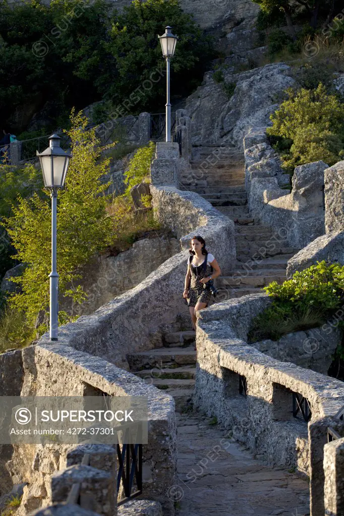 Europe, San Marino. Young woman walking down the steps of one of the three castles overlooking the city on Monte Titano. MR. UNESCO