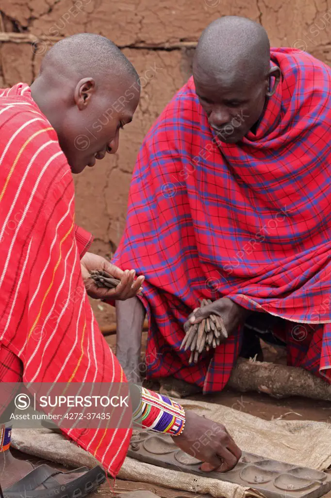 Maasai men play mancala at a manyatta in the Masai Mara, Kenya.