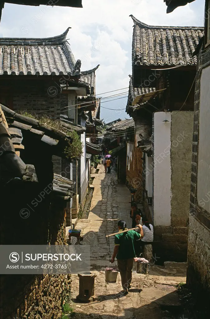 A Naxi women carries cooled beancurd through the lanes of the town's old quarter