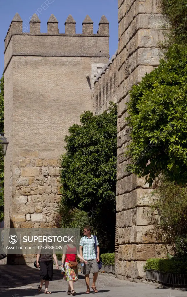 Spain, Andalusia, Seville; Tourists walking in front of fortified walls in the historic centre