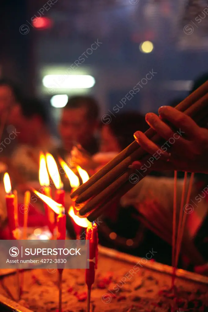 A visitor lights incense sticks at the Buddhist shrine in the Man Mo Temple in Sheung Wan, Hong Kong Island