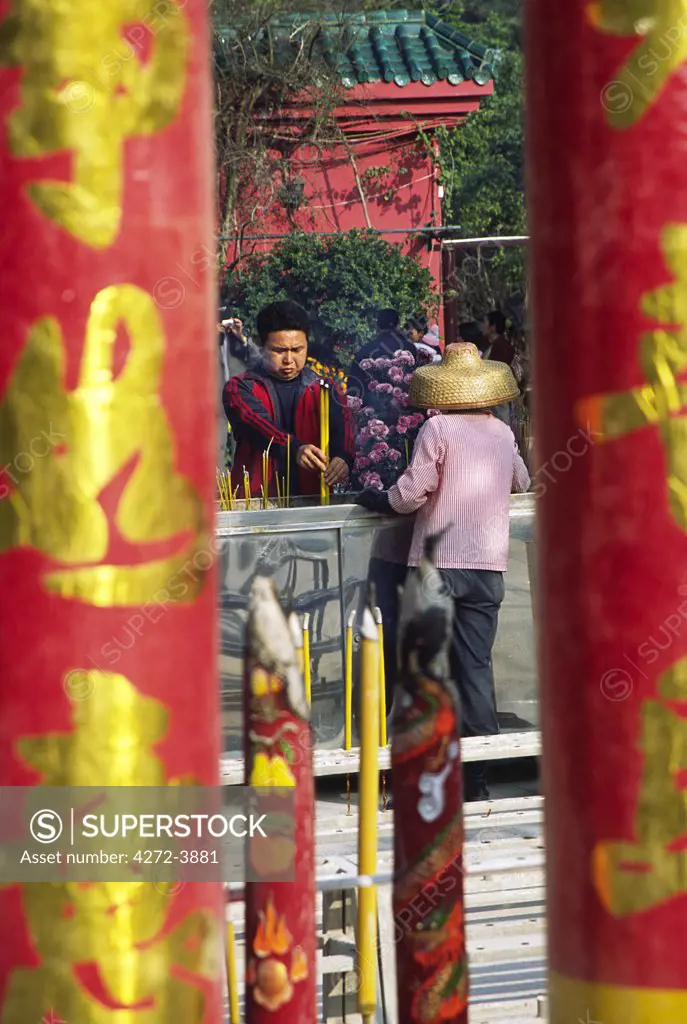 Looking through giant joss sticks to a visitor making an incense offering at the Po Lin Monastery on Lantau Island, Hong Kong