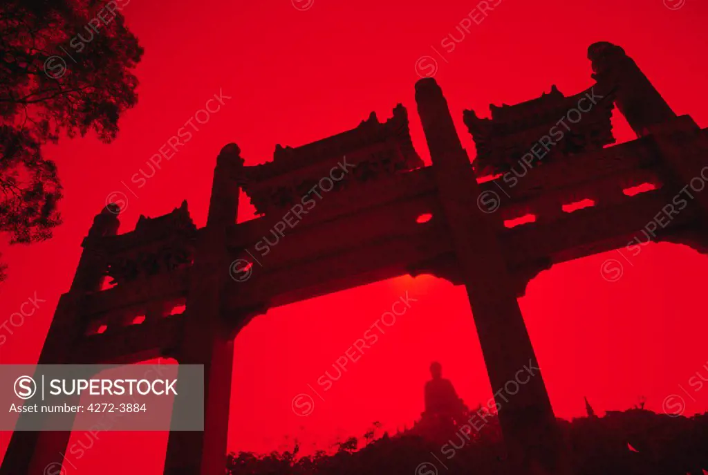 CHINA, Hong Kong, Lantau Island, Ngong Ping. The Tian Tan Buddha is framed by a chinese gate at Ngong Ping on Lantau Island, Hong Kong.  The Tian Tan Buddha is the world's largest outdoor, seated, bronze Buddha in the world.