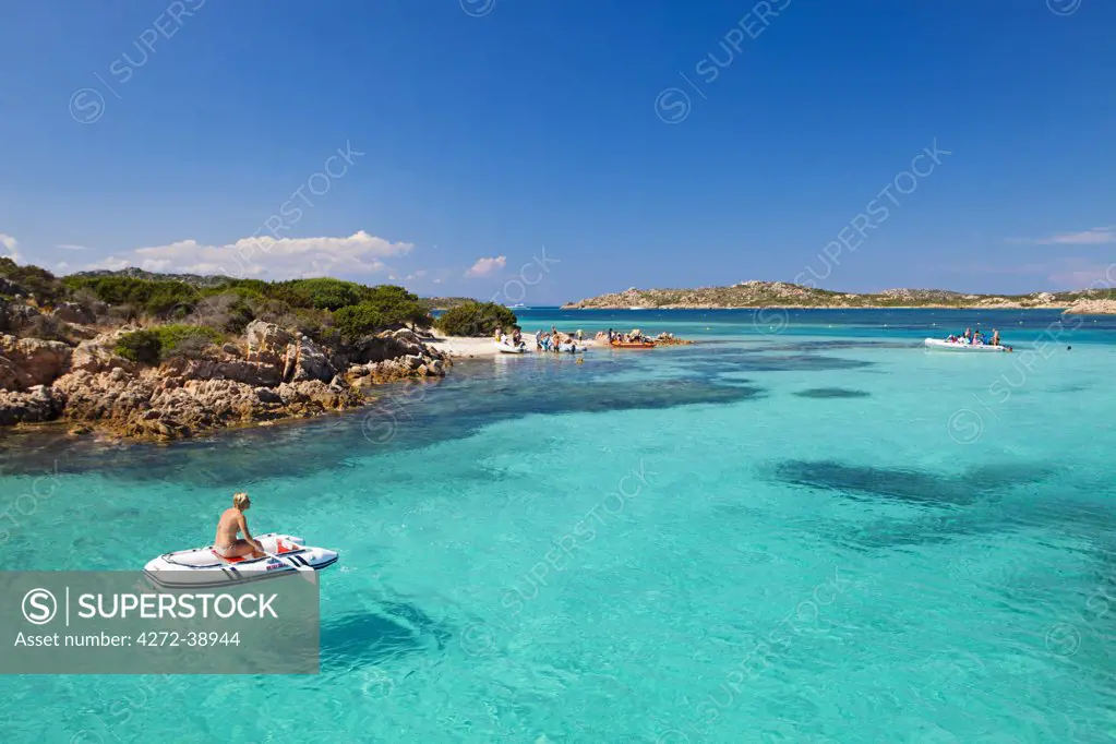 Italy, Sardinia, Olbia-Tempo, La Maddalena Archipelago. A woman sits on a boat  next to Budelli Island.