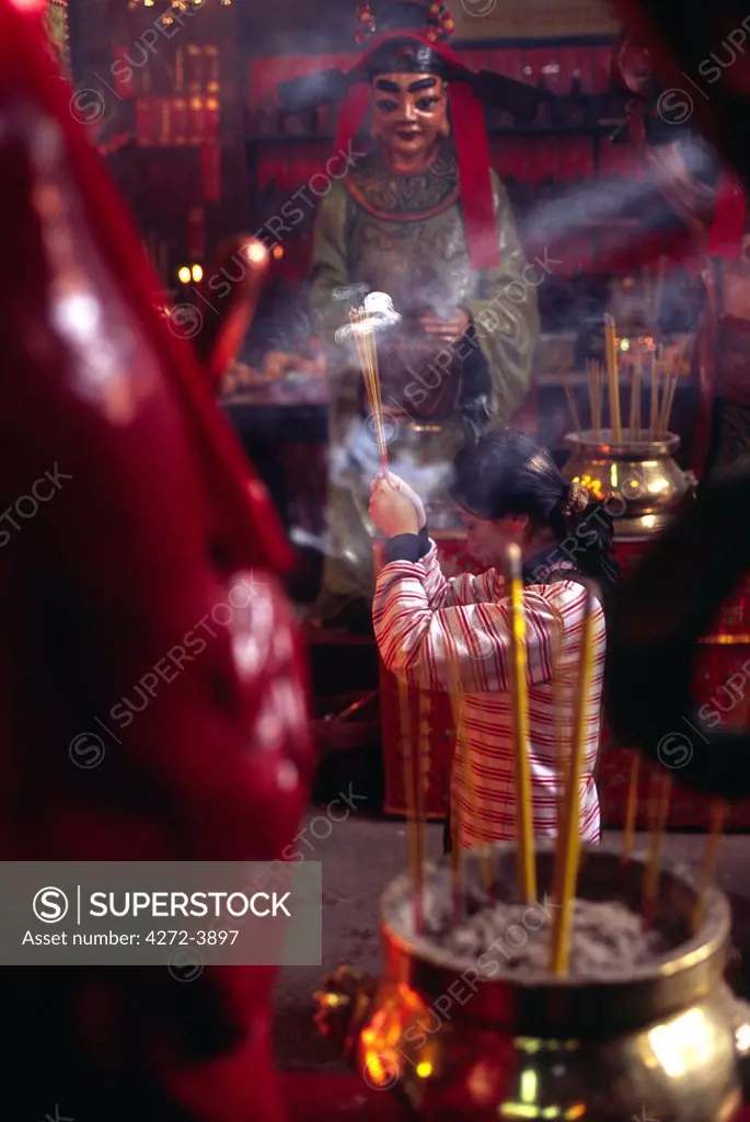 A visitor offers incense at the shrine of the Man Mo Temple in Sheung Wan on Hong Kong Island. The busy 18th century temple is one of Hong Kong's most famous and is dedicated to the deities of Man Cheung and Kwan Yu.