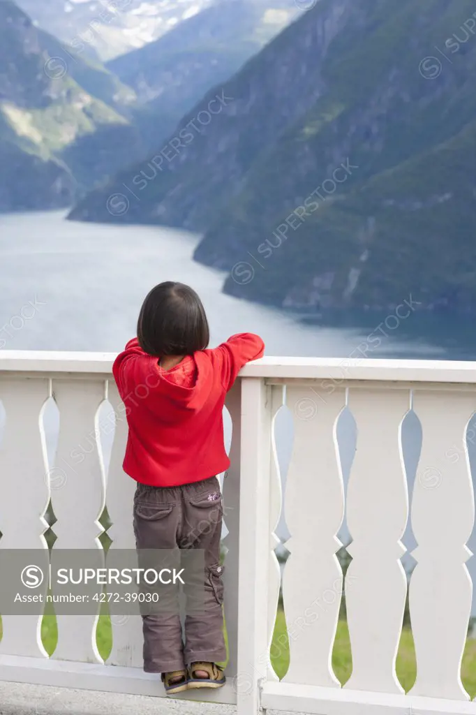 Norway, Western Fjords, Norddalsfjord, girl standing on fence looking at fjord (MR)