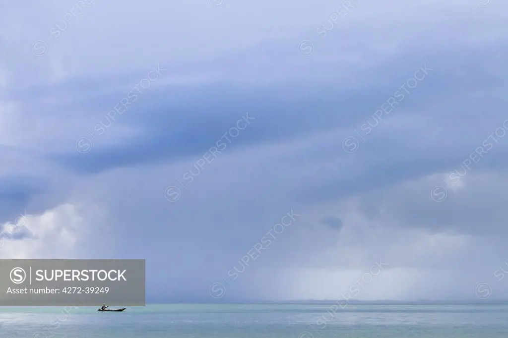 Africa, Sierra Leone, Southern Province, Turtle Islands. A man rows a boat while a rain storm approaches.