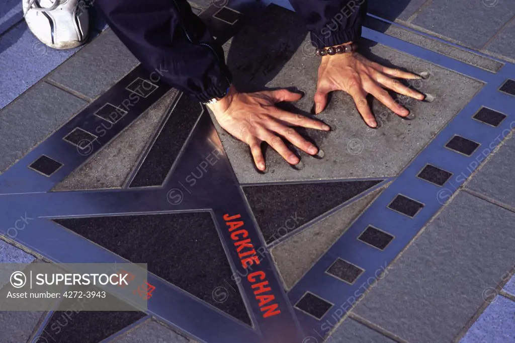 A visitor tries out the hand prints of film star Jackie Chan on Hong Kong's Avenue of the Stars on the Kowloon waterfront