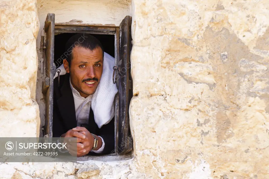 Yemen, Sana'a Province, Haraz Mountains, Al Hajjarah. A man looks out from a window.