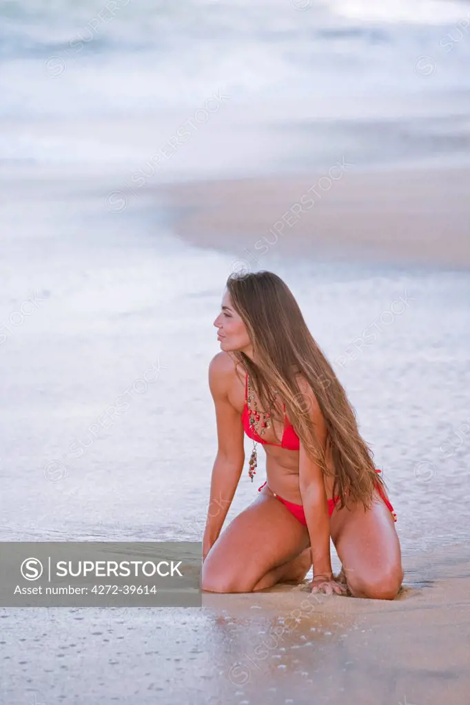 Brazil, Bahia, Trancoso, Espelho beach, model on the beach in a red bikini. MR