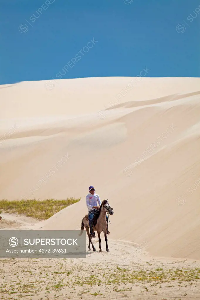 South America, Brazil, Maranhao, horseman riding through the sand dunes in the pequenos Lencois coastal desert between Cabure and Tutoia