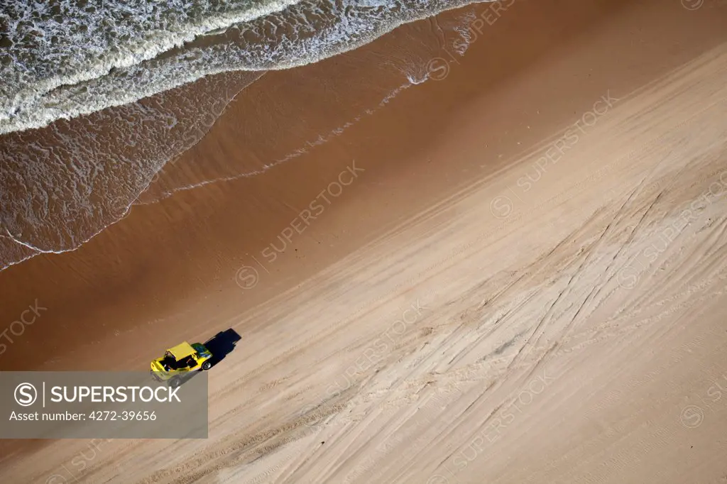 South America, Brazil, Ceara, Fortaleza, Aerial view of a yellow beach buggy driving along a beach between Jericoacoara and Fortaleza