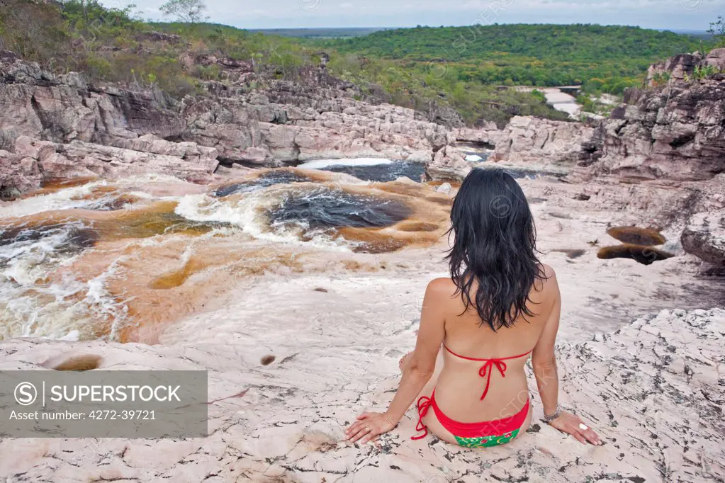 Brazil, Bahia, Chapada Diamantina. A model in a bikini looks out over the Roncador waterfalls in the Chapada Diamantina National Park MR