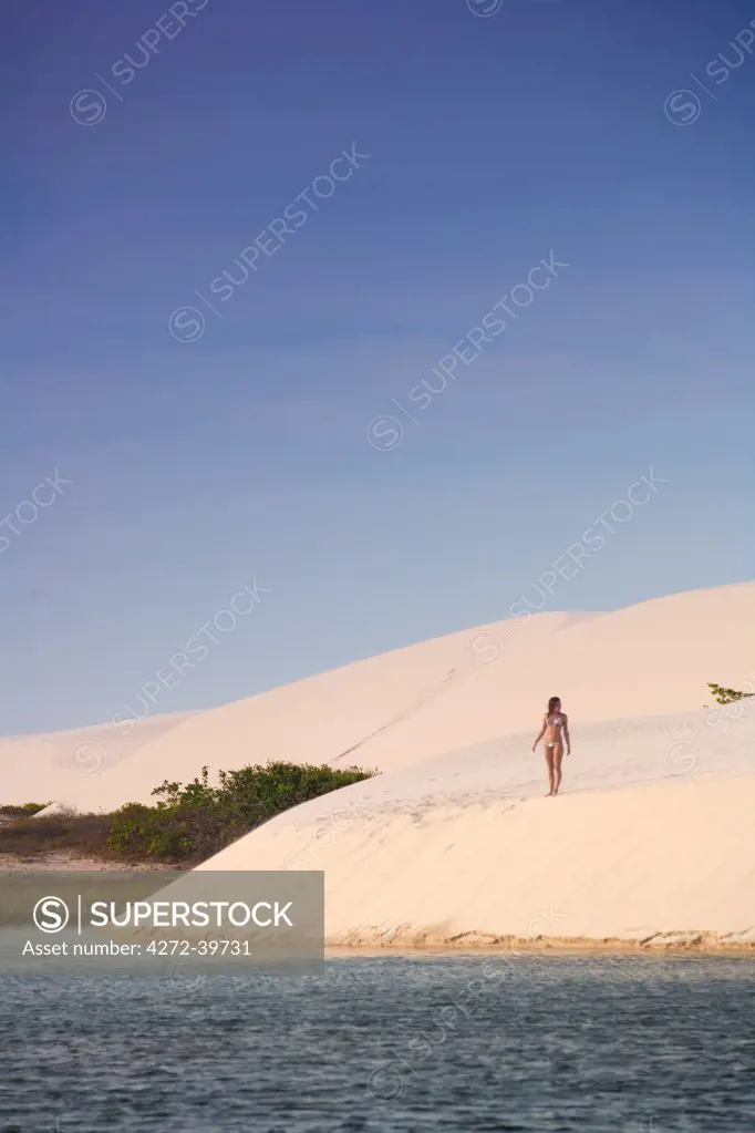 South America, Brazil, Maranhao, a woman in a bikini descends a dune in the Lagoa do Peixe in the Lencois Maranhenses