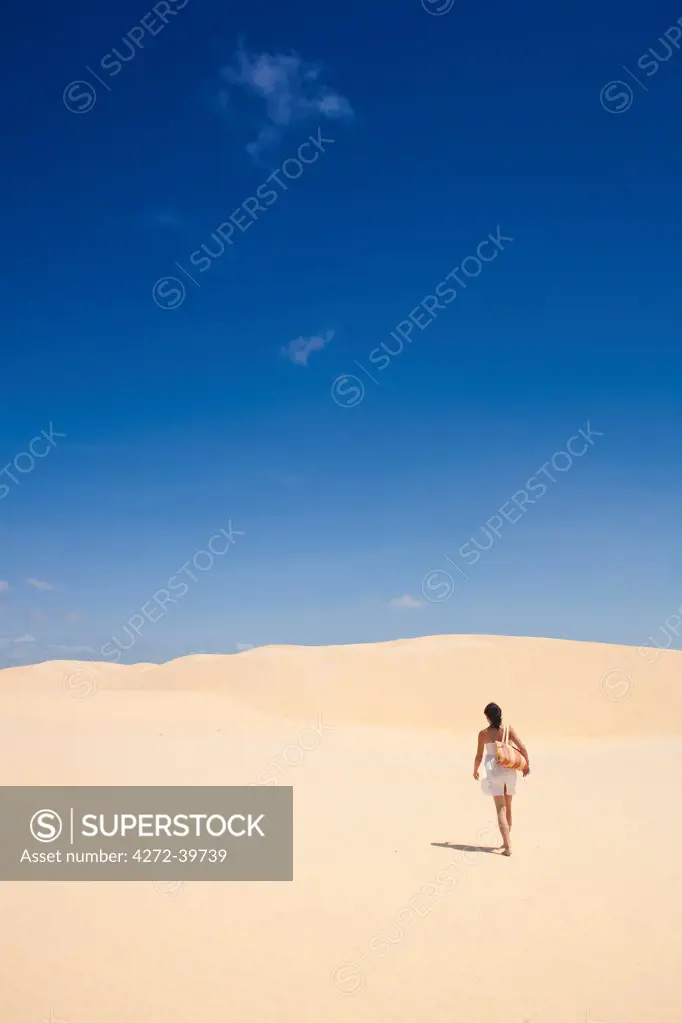 South America, Brazil, Maranhao, Vassouras, woman in a raw cotton dress walking in the sand dunes in the pequenos Lencois coastal desert MR