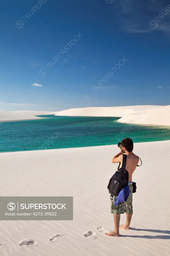 South America, Brazil, Maranhao, an ecotourist with a canon camera walks across dunes and lakes in the Lencois Maranhenses
