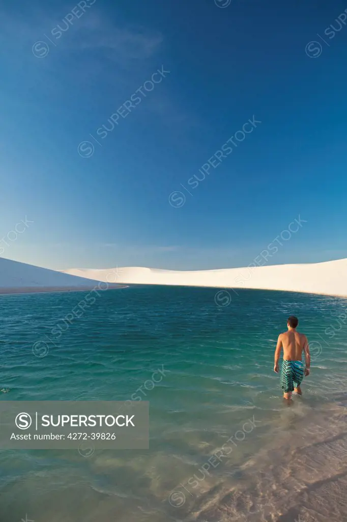 South America, Brazil, Maranhao, a swimmer enters a lake surrounded by dunes in the Lencois Maranhenses