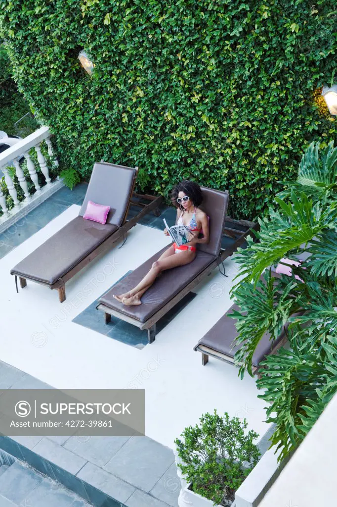 Brazil, Rio de Janeiro city, Gavea, La Maison Hotel, model in a Brazilian bikini sitting on a sun lounger next to the pool in the La Maison boutique hotel MR PR