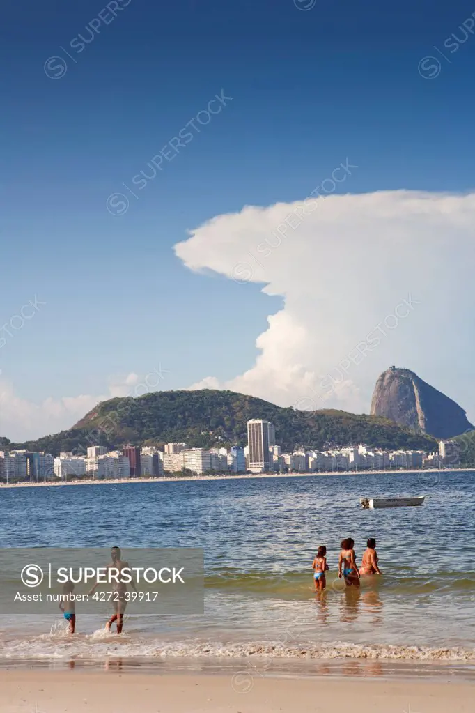 South America, Rio de Janeiro, Rio de Janeiro city, swimmers at the end of Copacabana Beach with Copacabana and the Morro do Leme hill in the background