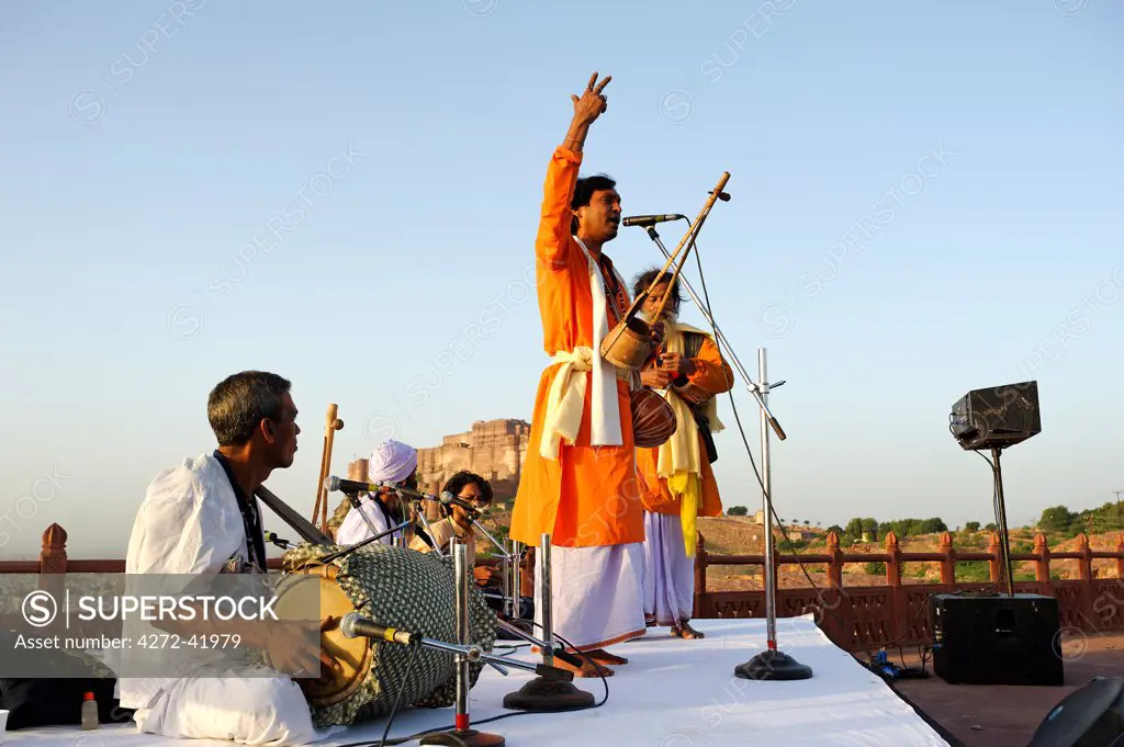 India, Rajasthan, Jodhpur. Framed by the massive Mehrangarh Fort, Baul musicians at the Rajasthan International Folk Festival,  perform at one of the dawn recitals.