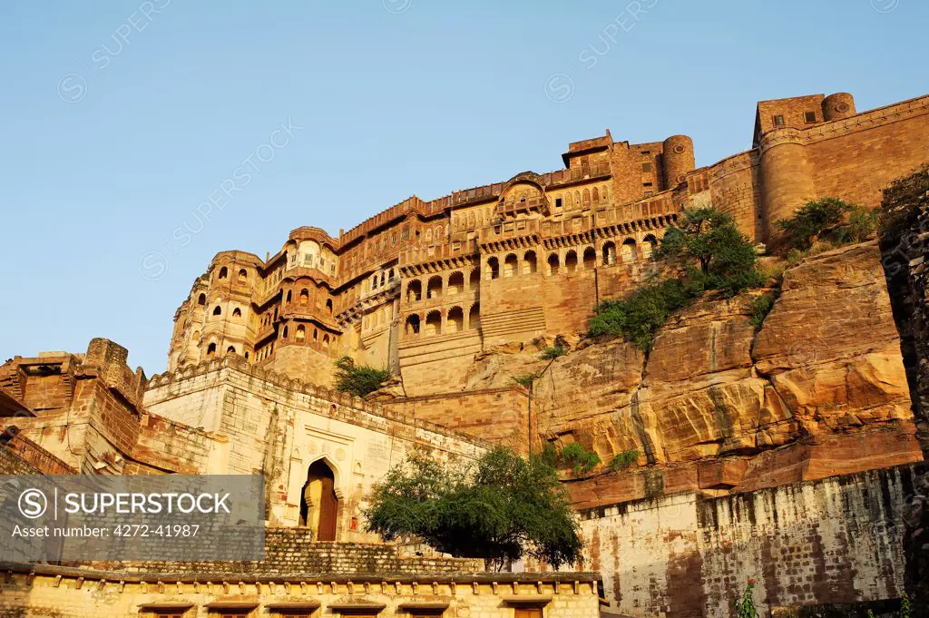India, Rajasthan, Jodhpur. Perched atop a sheer rocky bluff, the main palace buildings of Mehrangarh Fort are guarded by a muscular arrangement of fortifying walls and gateways.