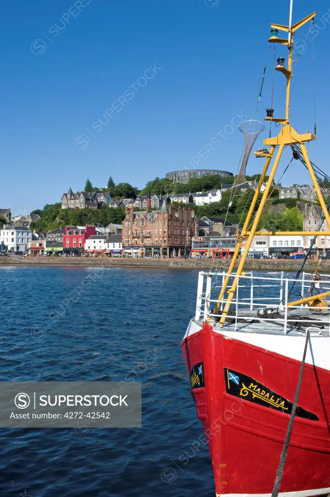 Scotland, West Coast, Oban. View of Oban harbour with fishing boat and McCaig's Folly on the hill behind.