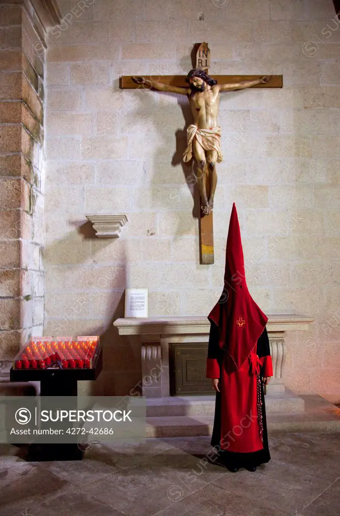 Santiago de Compostela, Galicia, Northern Spain, A nazareno standing beside a cross in a church during Holy Week