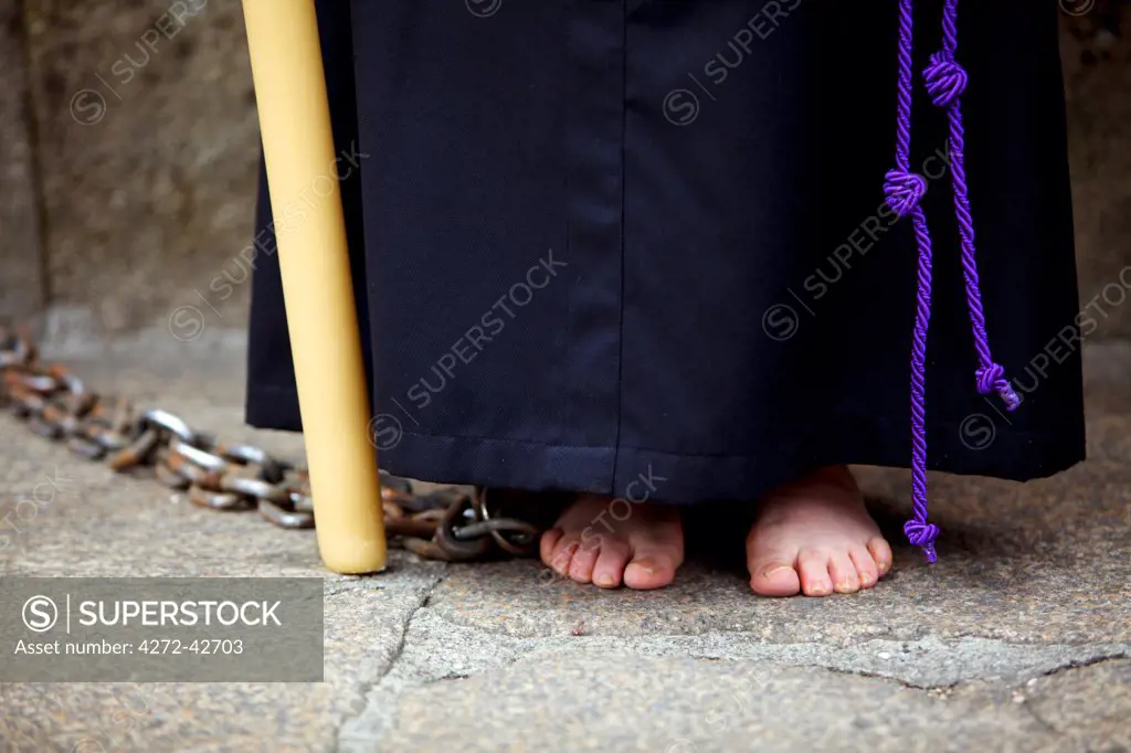 Santiago de Compostela, Galicia, Northern Spain, Detail of a Nazareners robe with a rope serving as a belt, chains, feet and a candlestick during Semana Santa